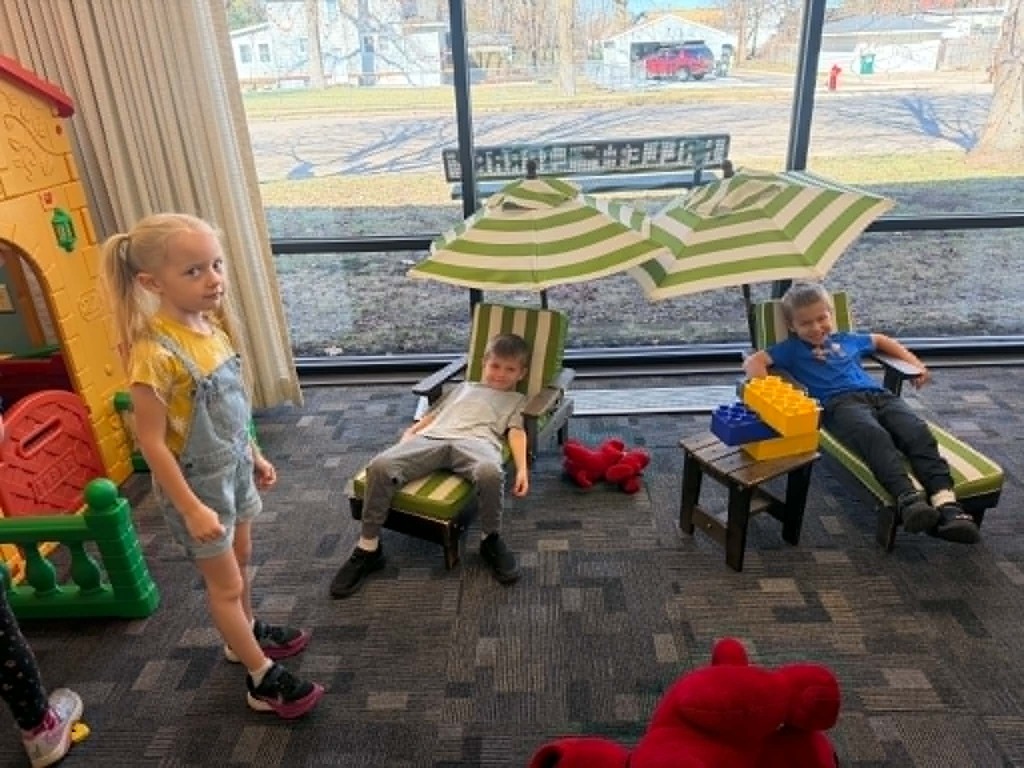 three kindergartners sitting on beach chairs