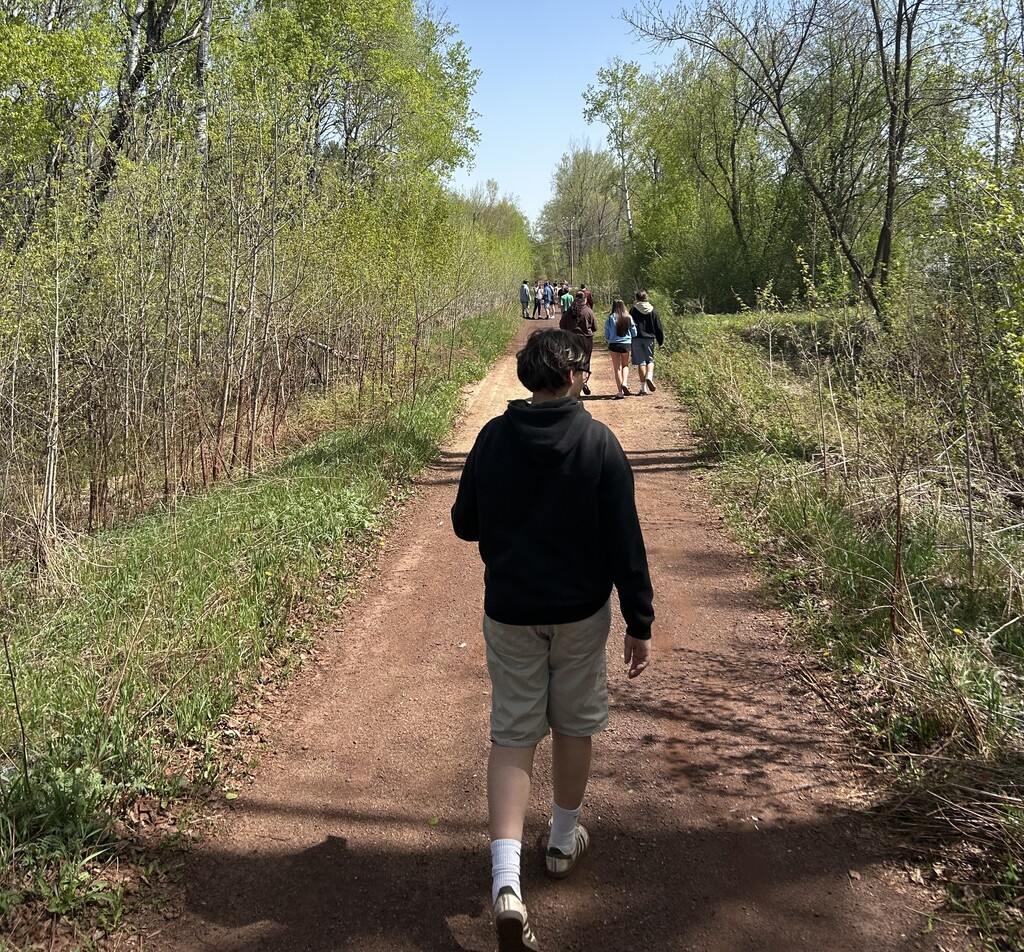 multiple students on the trail near the school looking for something to take a photo of for class