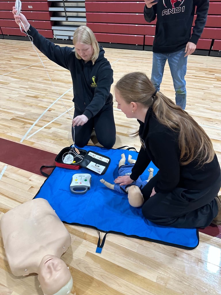 two females one doing cpr on a baby the other getting an AED ready