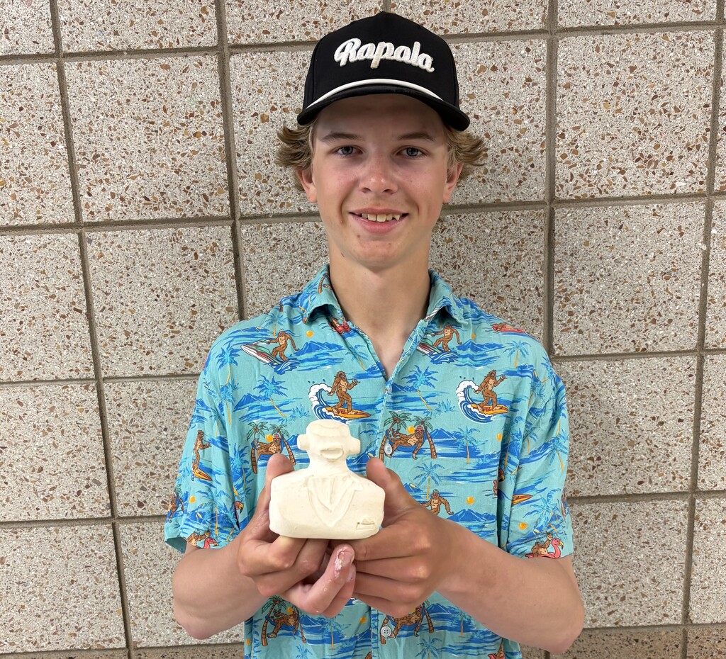 male student holding a handbuilt bust project