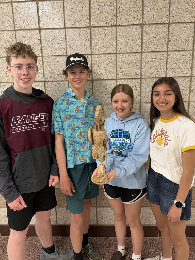 four students who worked on a group project and made a cardboard creature