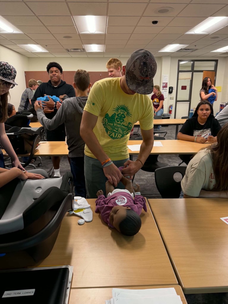 male student learning how to change a babies diaper
