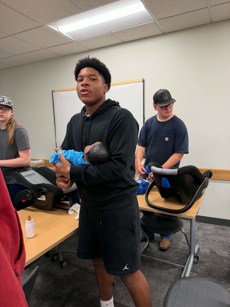 male student holding a baby in health class