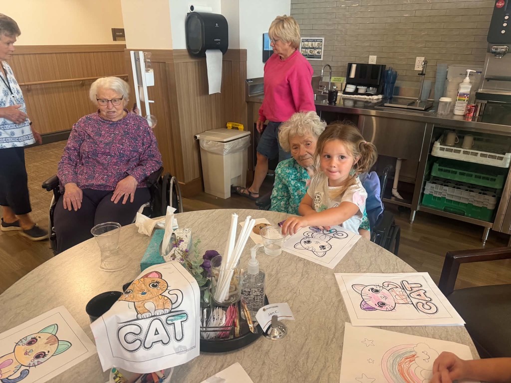 kindergartner sitting on a residents lap while coloring at heartwood
