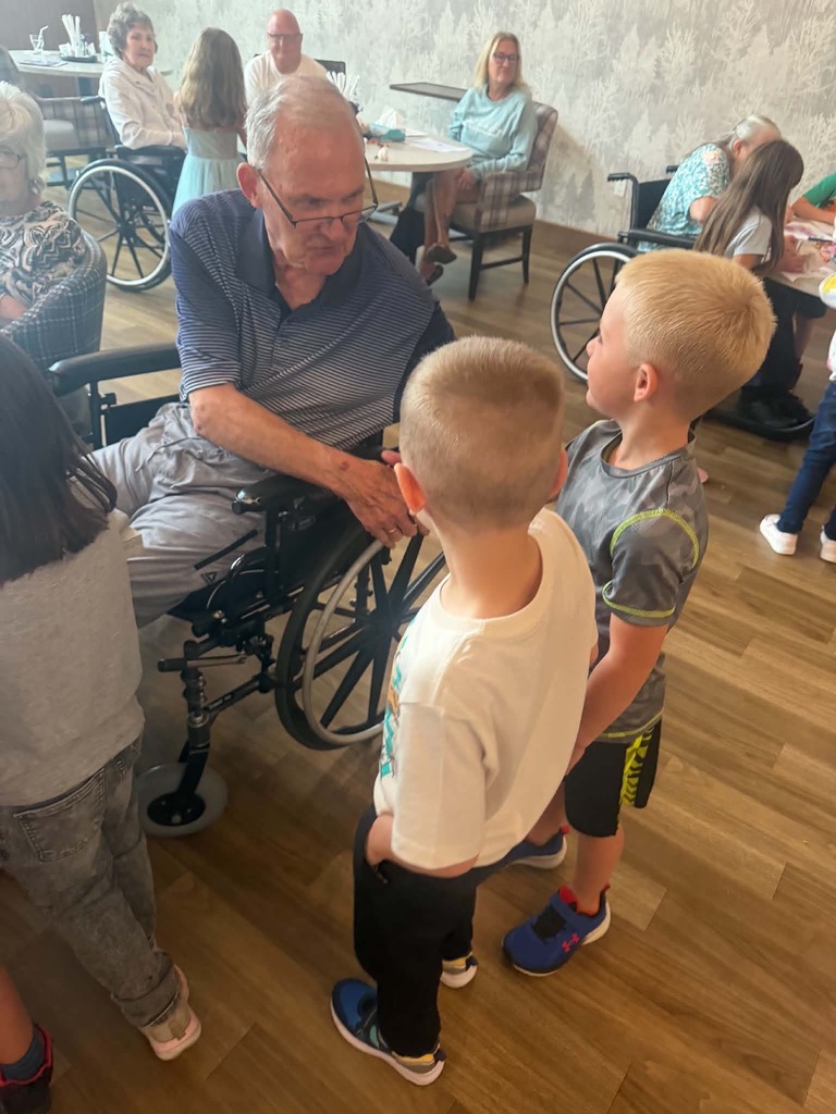 resident shaking hands with two kindergarten boys