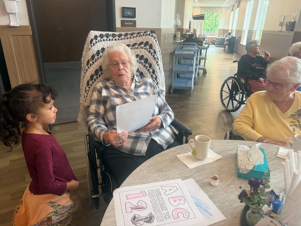 a kindergartner showing a resident her coloring page