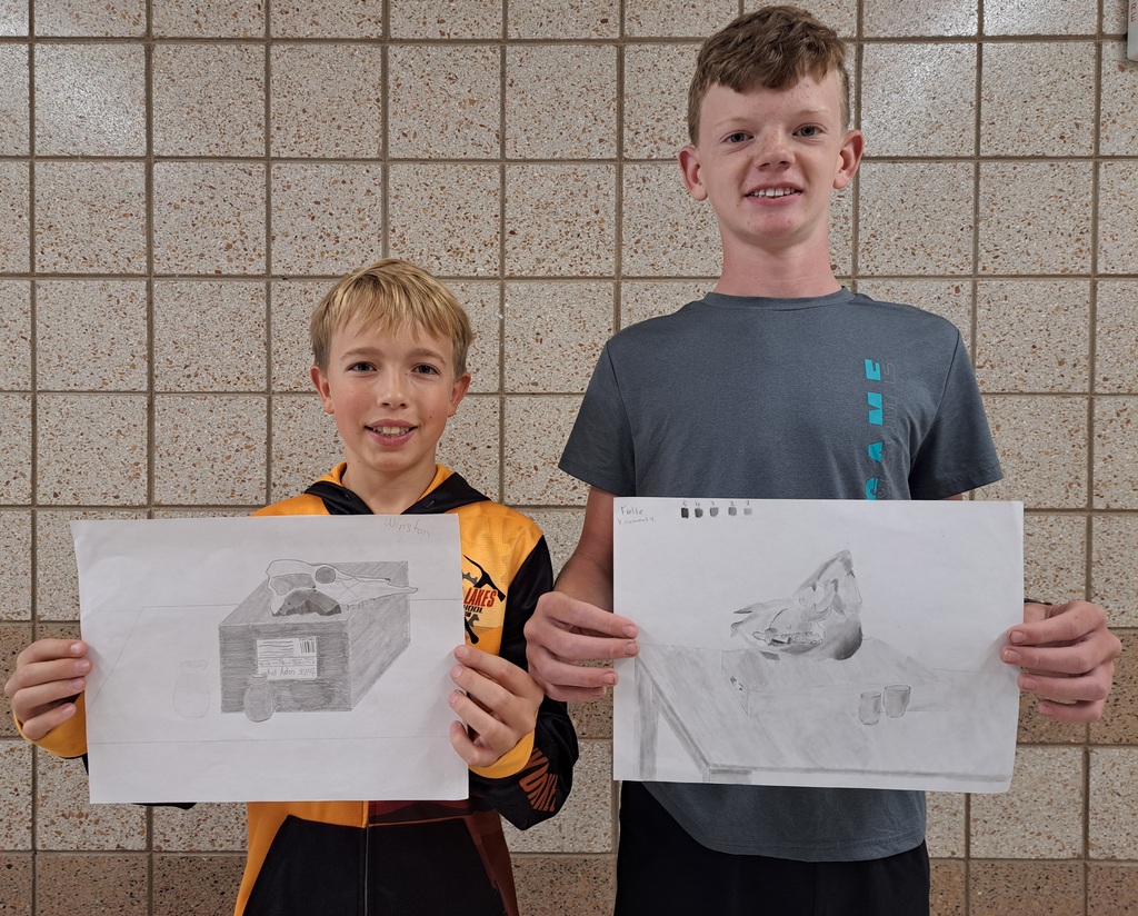 two male students holding their perspective drawings