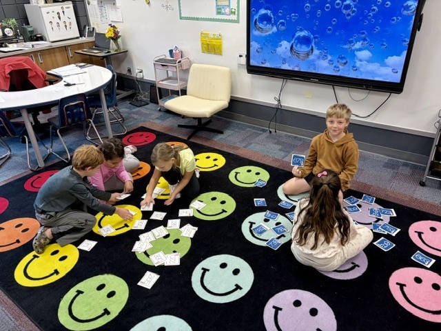 5- 2nd graders sitting on a smiley face run sorting numbers