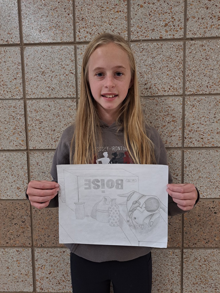 8th grade female student holding a still life drawing