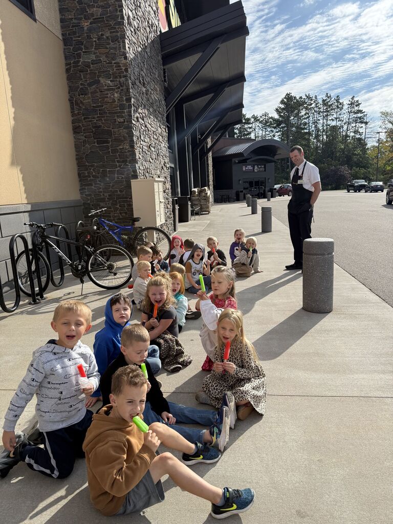 Kindergarteners sitting outside of Super One eating popsicles