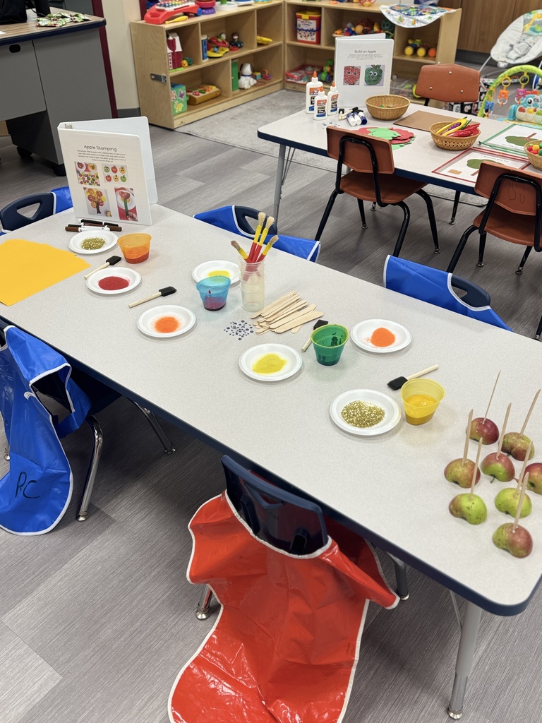 a table at ECFE that has paints, halved apples and popsicle sticks