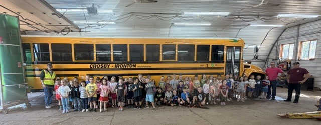 all kindergartners at the bus garage in front of a bus