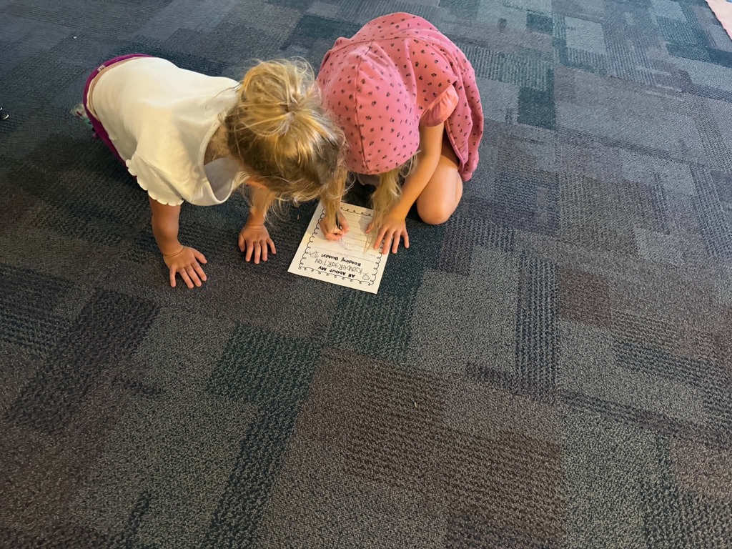 two females on the floor filling out a piece of paper together