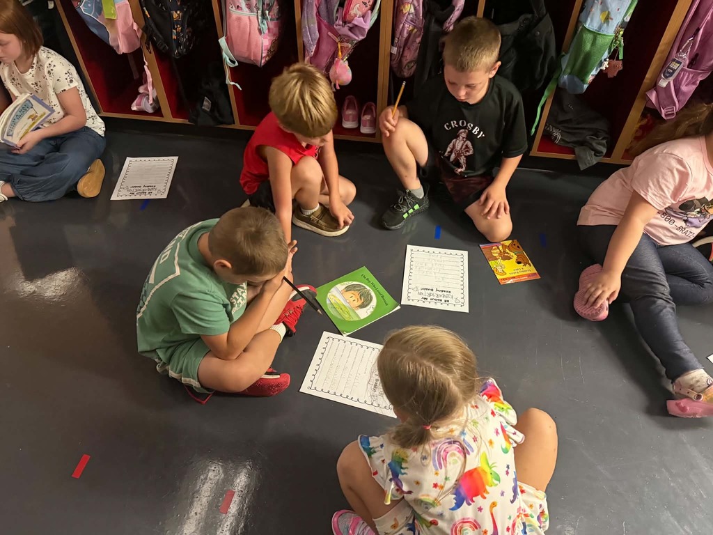 multiple 2nd graders and kindergartners meeting in the locker bay to read togehter