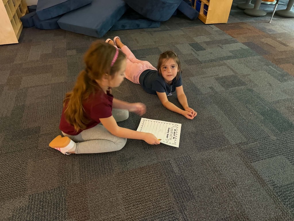 two females, one laying on the floor the other filling out the piece of paper