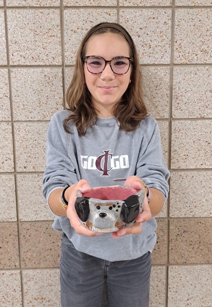 female studen holding a pinch pot of a dog