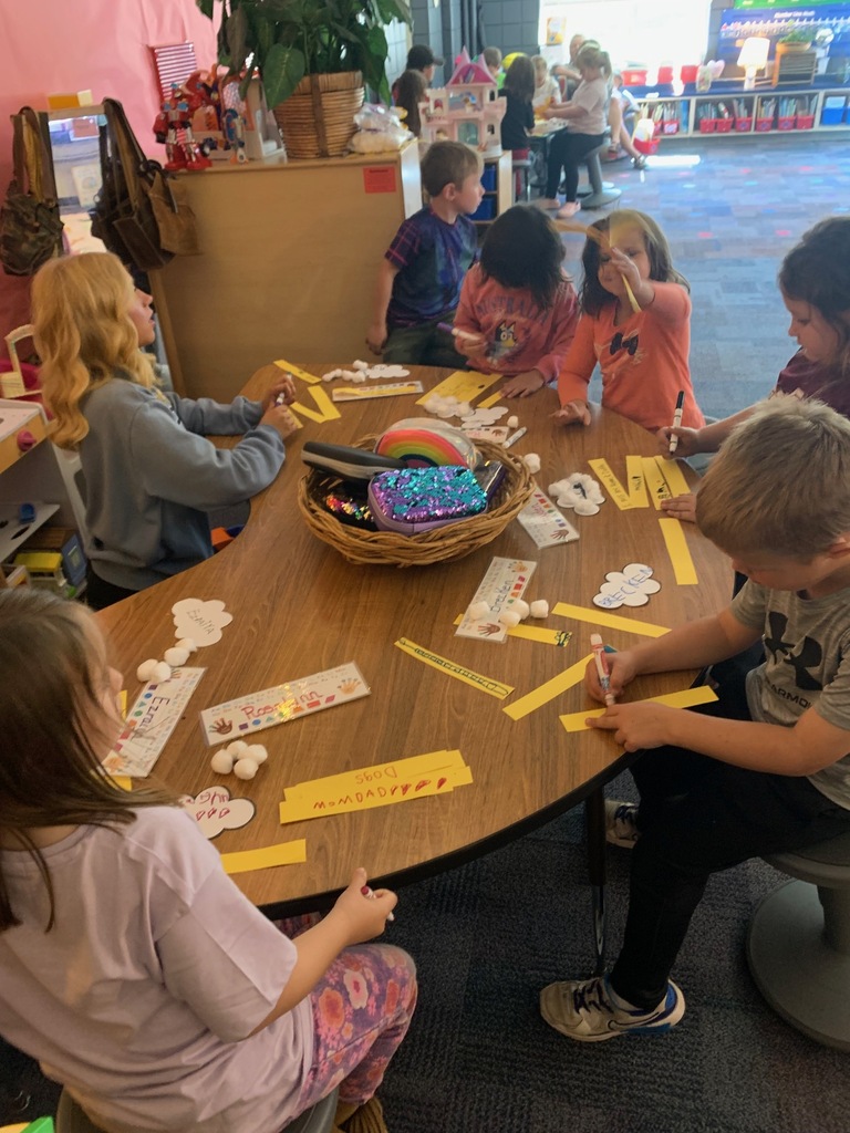 students writing on yellow pieces of paper sitting at a table with a HS student
