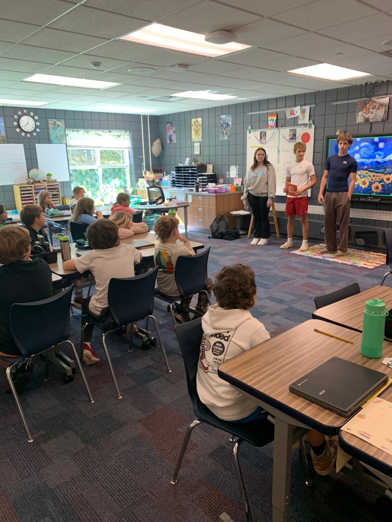 three HS students standing in front of a class at CRES for their Children's lit class