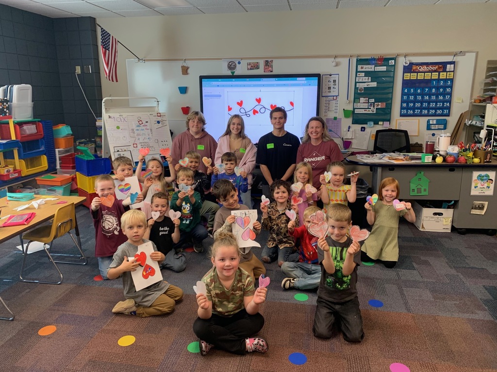 kindergarten students holding oaoerhears that they made with their HS children literature students and teacher