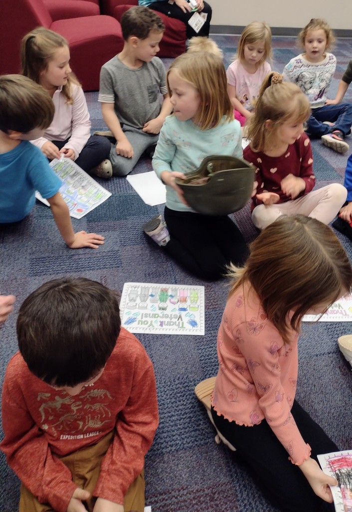 students sitting and one holding a hat