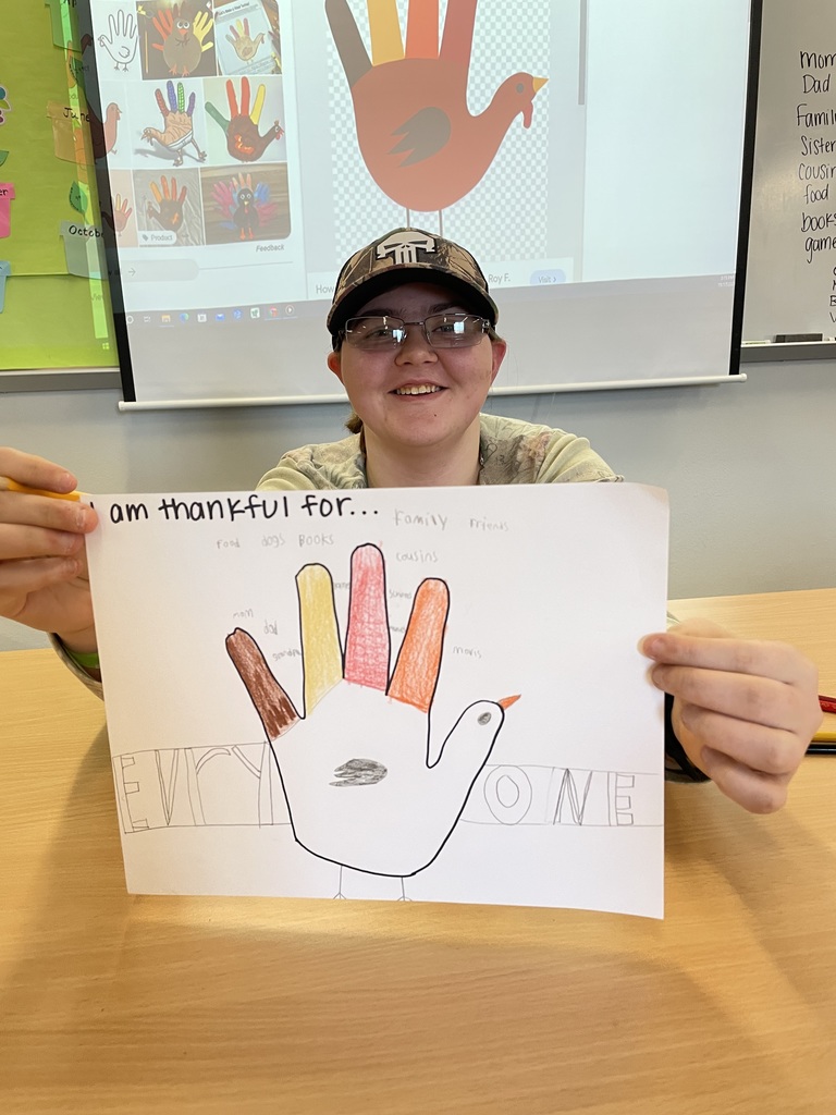 student sitting holding a hand turkey