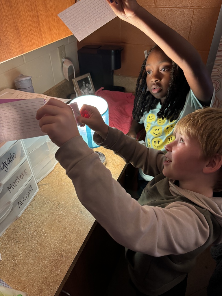 Students using lamp to look at paper.