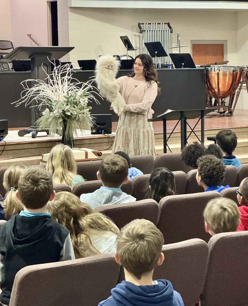 Lady with puppet speaking to children