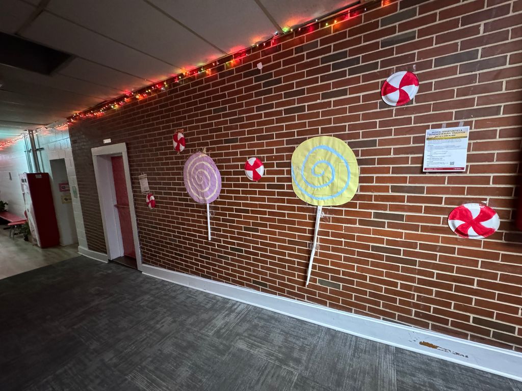The brick section of the halls decorated with Christmas lights and paper lollipops and paper plates decorates as peppermint discs