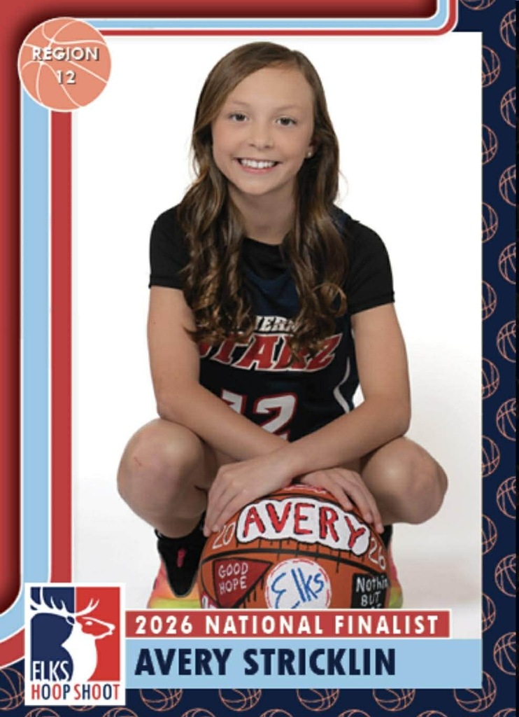 Smiling young girl wearing a black jersey with "ETAL" and number 12 sits holding a basketball. The background is white.