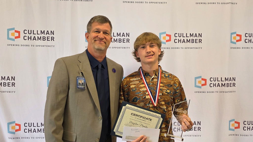 Two men stand for an award ceremony; one holds a certificate and medal, the other smiles.