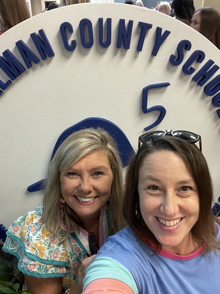 Two women smiling in front of a sign that says "County School 5".