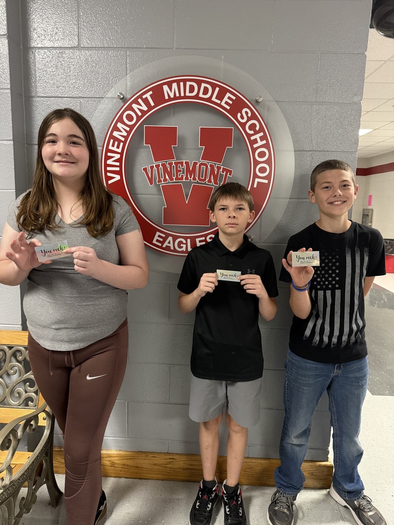 Three students stand before a sign that reads "Vinemont Middle School Eagles" in red and white.