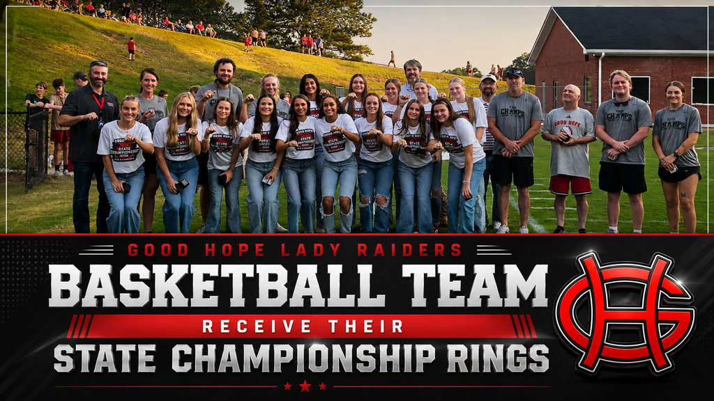 A group of people stand on a field, wearing matching shirts, and holding up rings. Behind them, a grassy hill and a building.