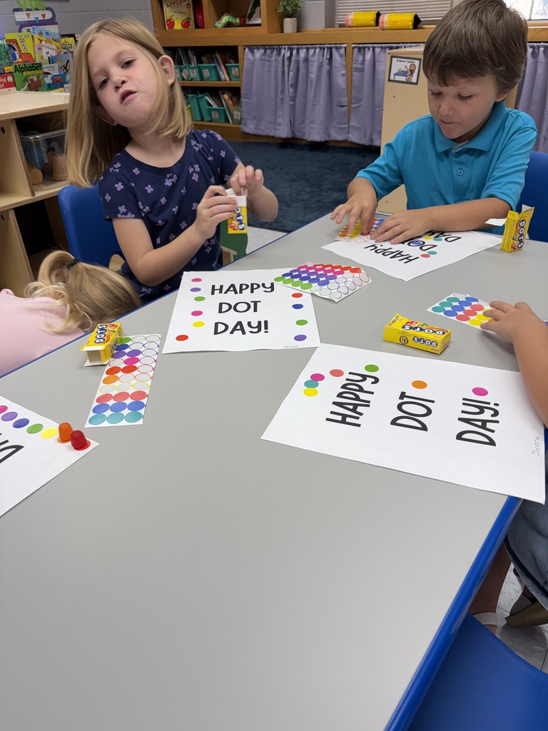 Children sit at a table with colorful papers that read Happy, Dot, Day, and Dad.