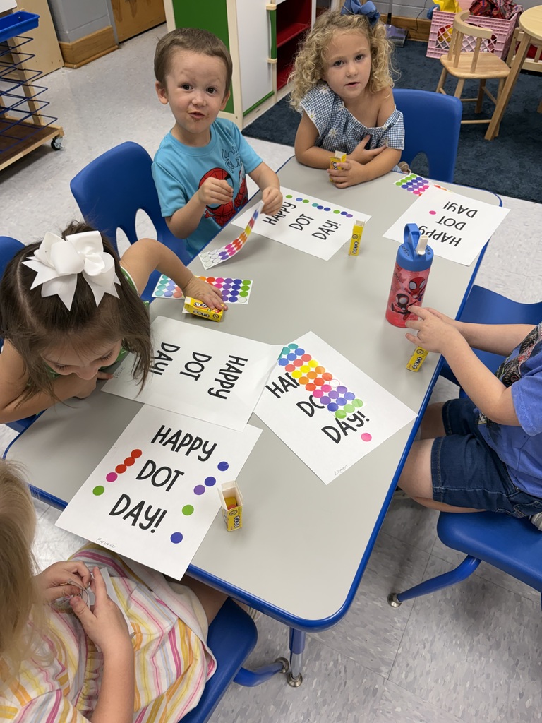 Children sit at a table with colorful papers and markers, engaging in an educational activity.
