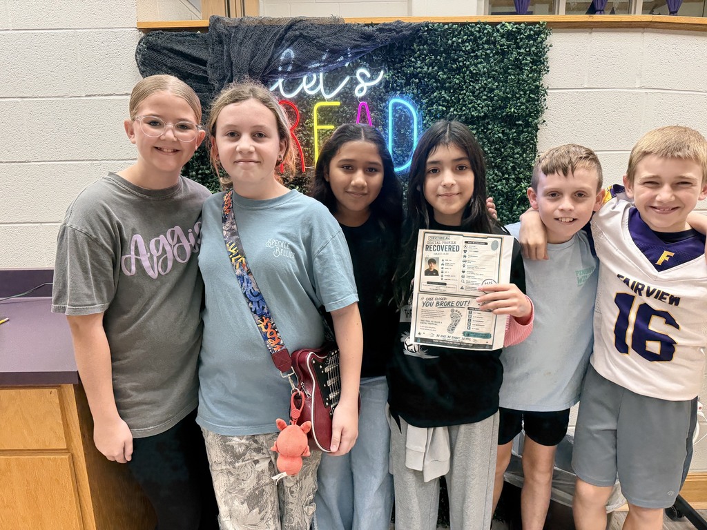 Six children pose together for a photograph, one holding a certificate, with a green wall in the background.