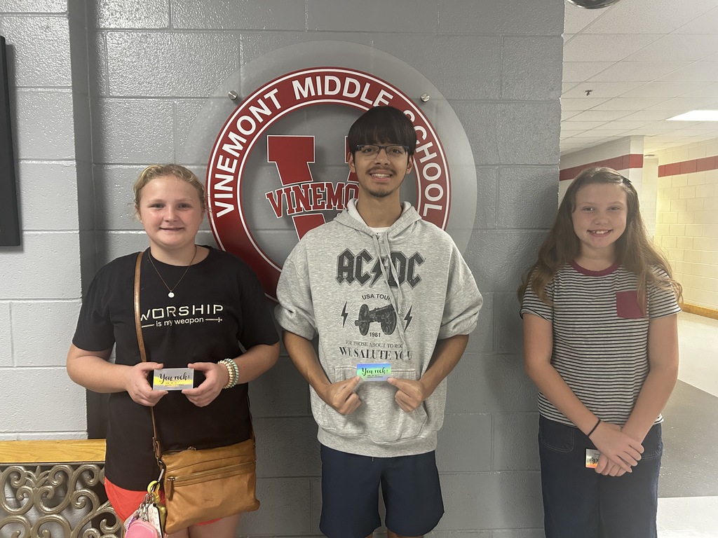 Three students pose in a school hallway; one holds a certificate. A Vinemont Middle School logo is behind them.