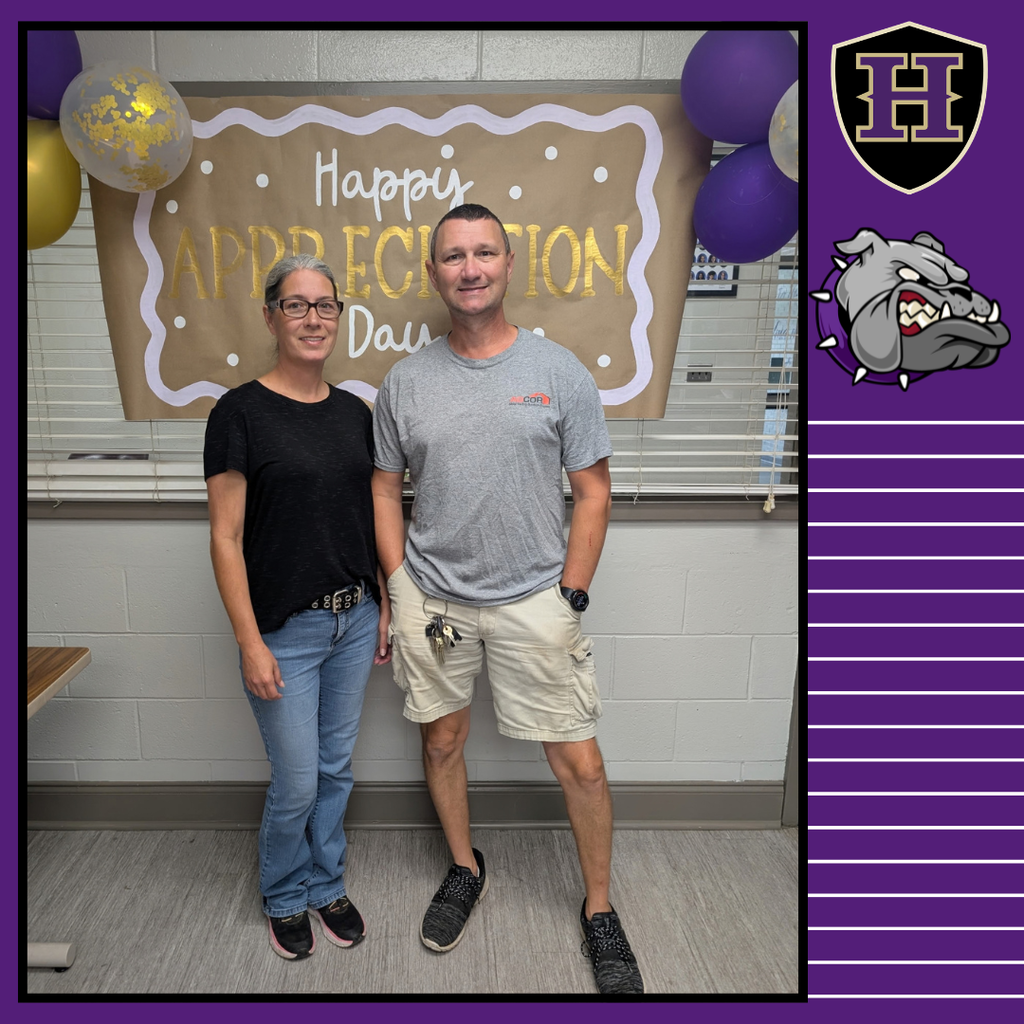 A man and a woman stand together indoors. A banner behind them reads "Happy Appreciation Day."