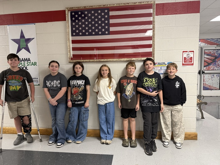 Students standing in a line, one with a cast on a leg, in a hallway with an American flag