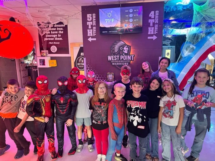 A group of children in costumes posing for a picture in a colorful room with balloons.