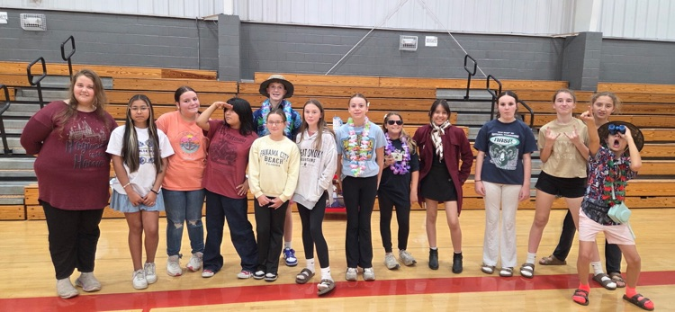 Several young people standing in a line on a basketball court in a gymnasium.