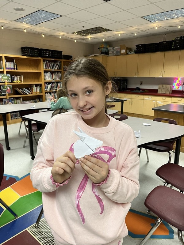 student with origami creation