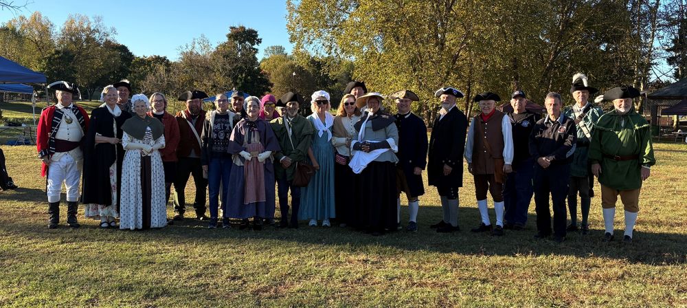 group of people dressed in historical outfits from the american revolution standing outside at a park