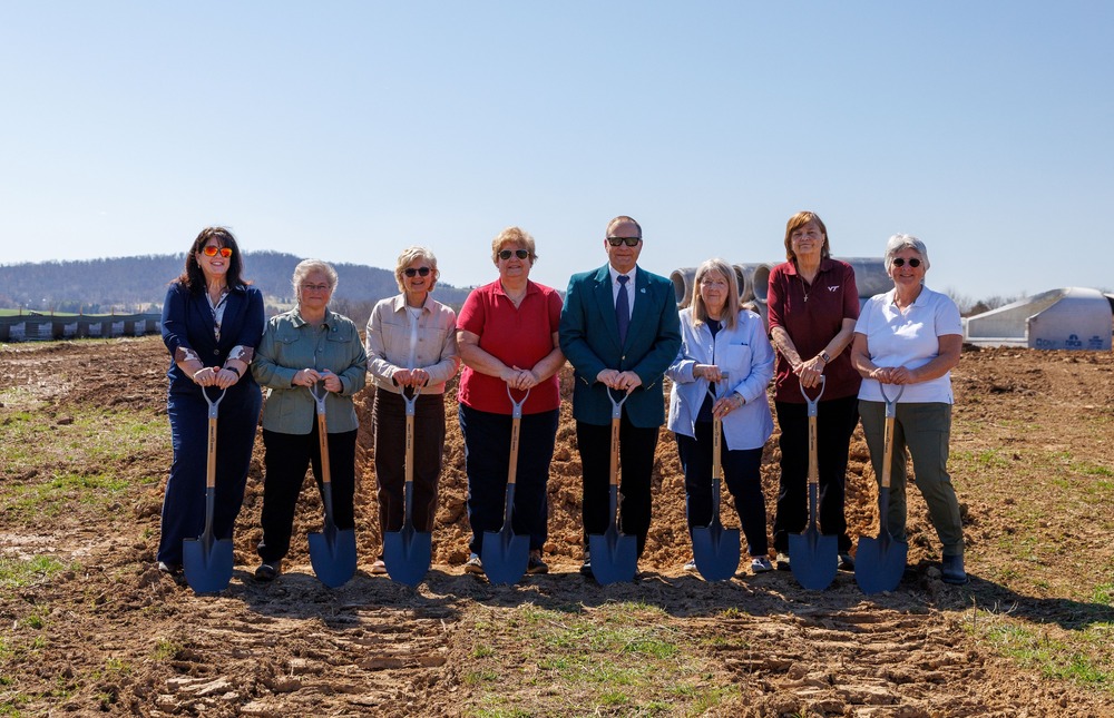 school board and superintendent standing outside in front of a construction site holding shovels 