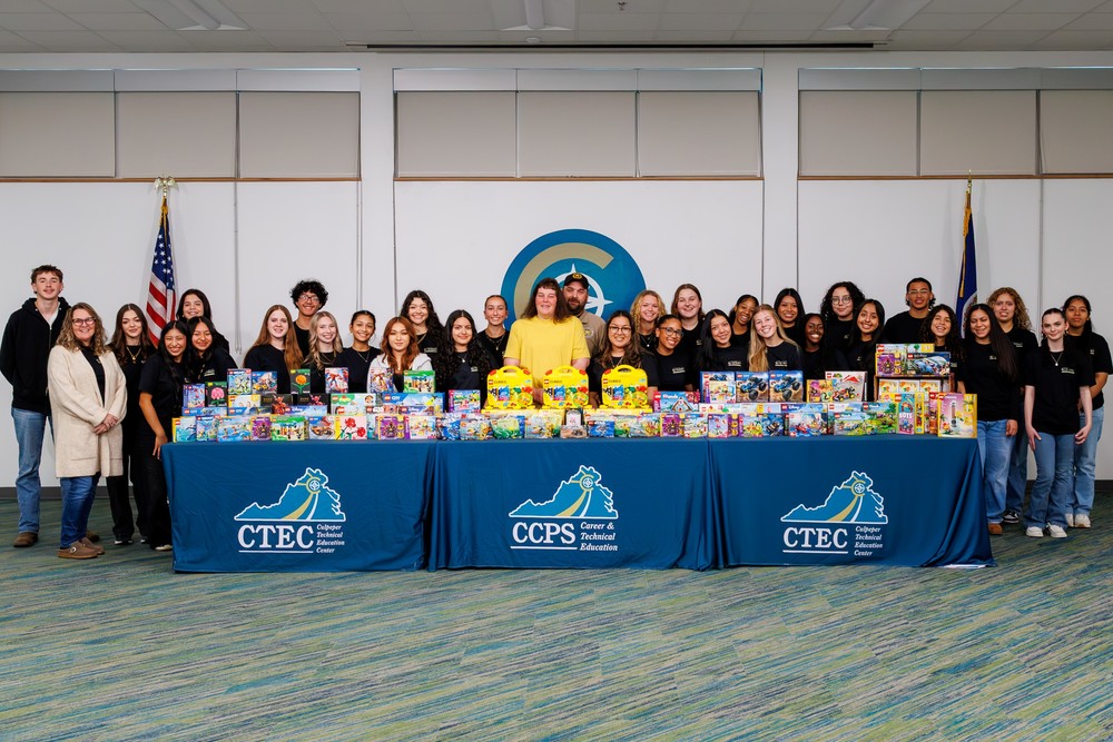 students standing behind tables filled with Legos with parents in the middle