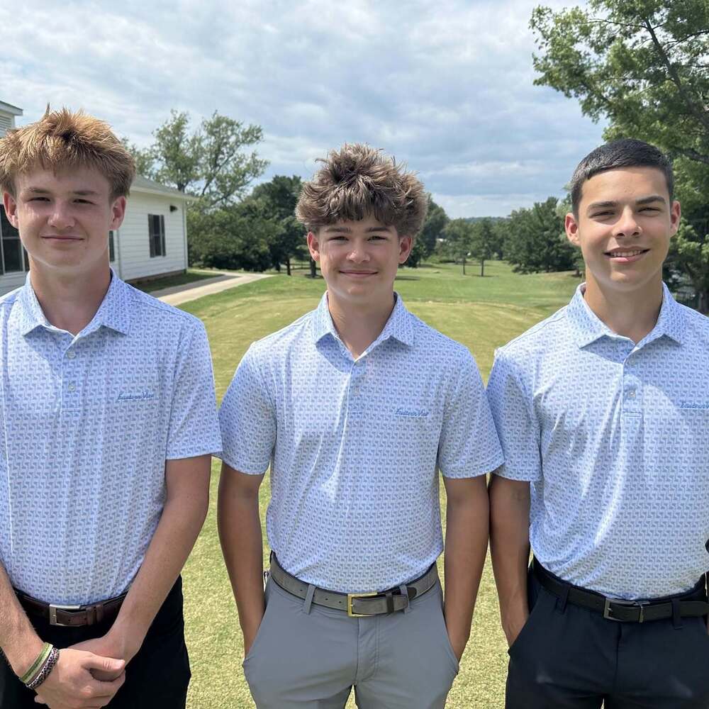 Three young men in light blue and white eastern view golf polos standing on the golf course
