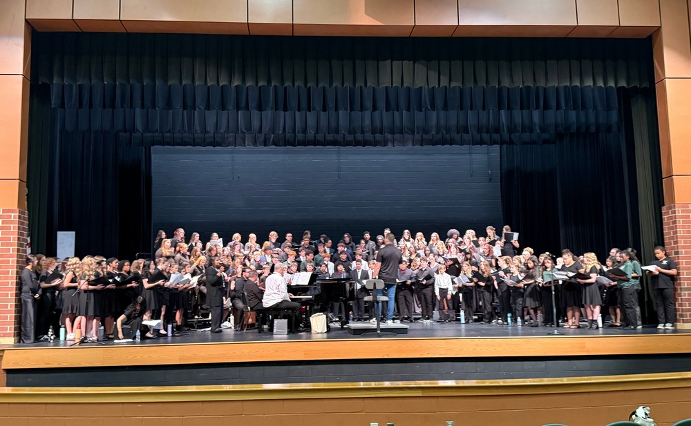 large group of students singing on a school stage