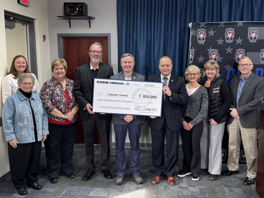 Congressman Eugene Vindman stands with Culpeper County and school officials while holding a ceremonial $850,000 check for the Simms Drive Extension Project during a Community Project Funding announcement at the Culpeper Police Department Community Room on February 27, 2026.