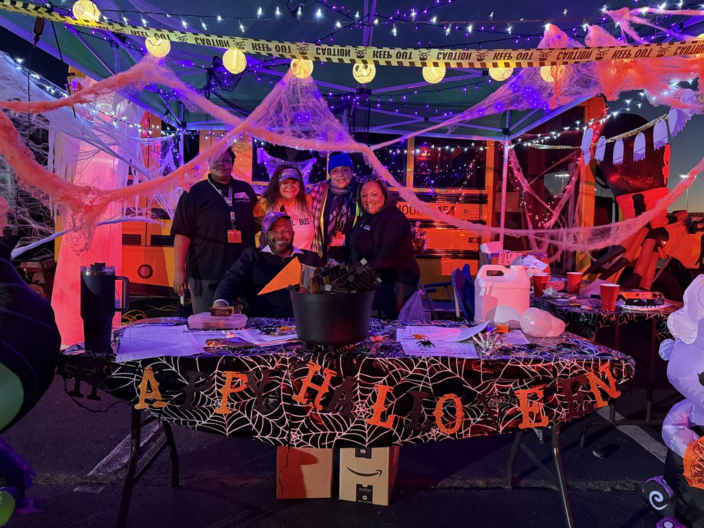 people standing in front of a school bus with halloween decorations