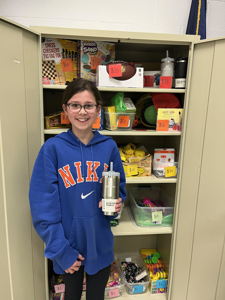 Female student holding up a Stanley cup in front of the school store